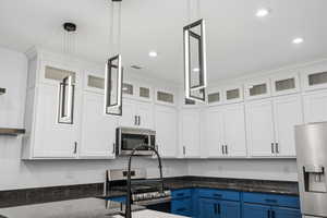 Kitchen with white cabinets, glass insert cabinets, appliances with stainless steel finishes, blue cabinetry, and recessed lighting