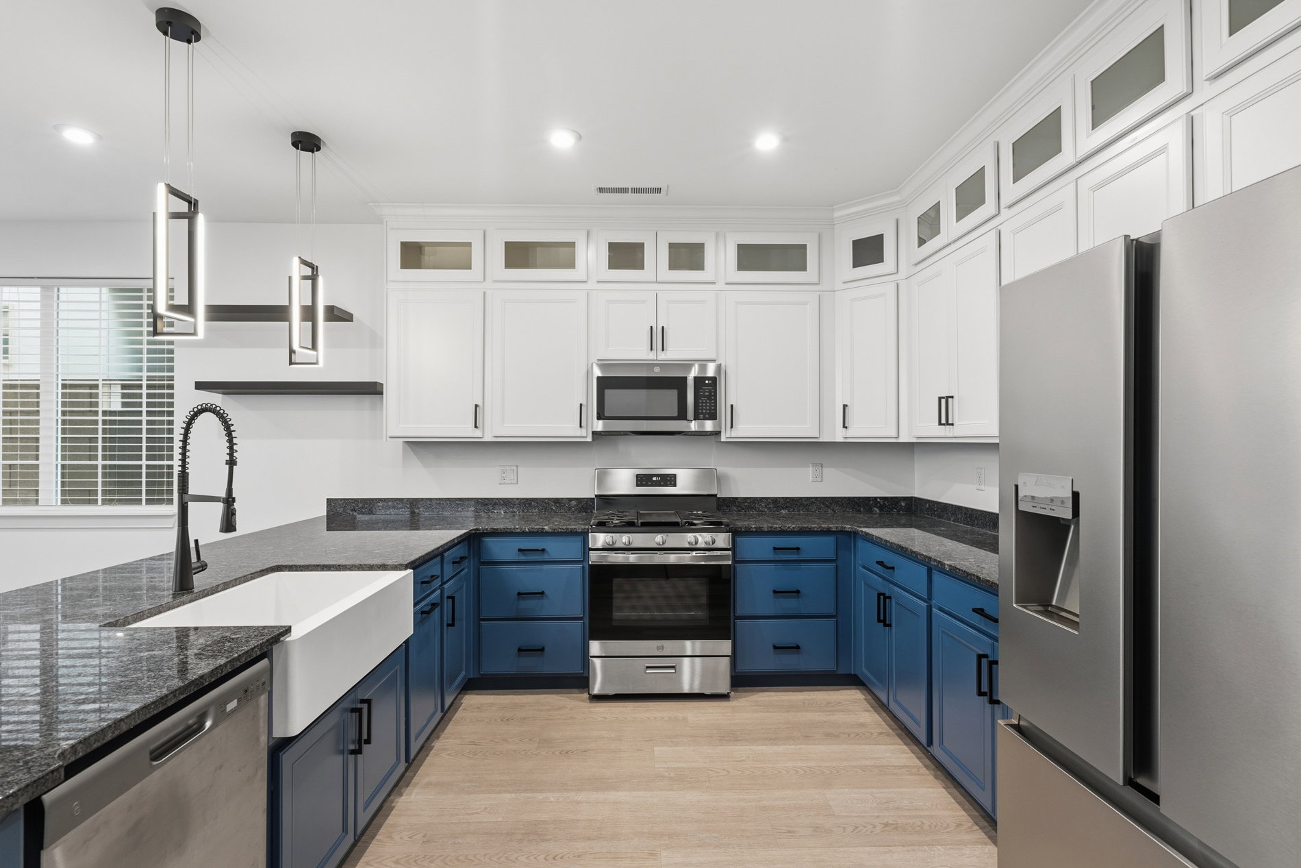 Kitchen featuring white cabinetry, blue cabinetry, stainless steel appliances, glass insert cabinets, and recessed lighting