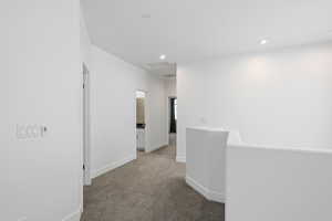 Hall featuring an upstairs landing, dark carpet, and recessed lighting