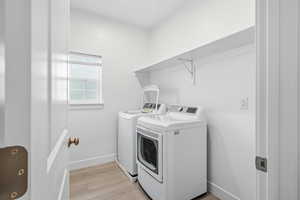 Laundry room featuring light wood finished floors and washer and clothes dryer