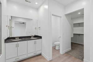 Bathroom featuring double vanity, a walk in closet, recessed lighting, light wood-style floors, and ceiling fan