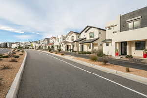 View of asphalt road featuring a residential view and curbs