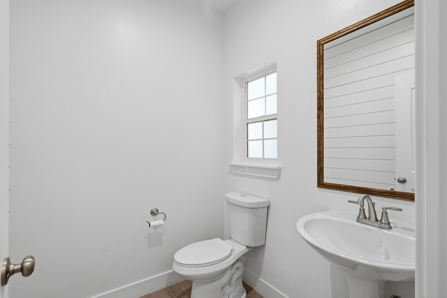 Half bathroom featuring toilet and wood finished floors