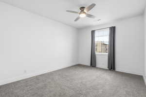 Spare room with light carpet and a ceiling fan