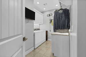 Washroom with cabinet space, light tile patterned floors, washer and clothes dryer, and recessed lighting