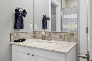 Bathroom with vanity, a shower with curtain, and tasteful backsplash