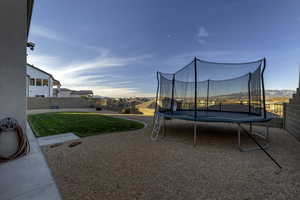 Fenced backyard with a trampoline, a patio area, and a residential view