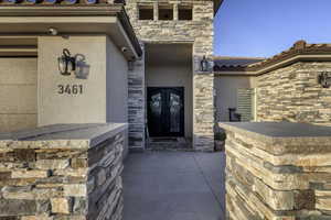 Entrance to property featuring stone siding, stucco siding, a tiled roof, and french doors