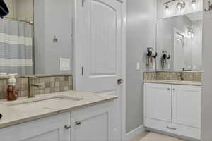 Full bathroom with vanity, backsplash, and curtained shower