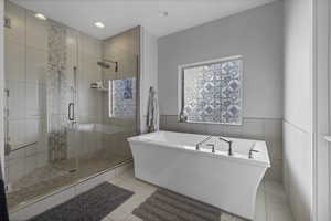 Full bath featuring a freestanding bath, a stall shower, a wainscoted wall, recessed lighting, and light tile patterned flooring