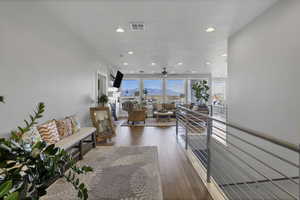 Corridor featuring dark wood-type flooring, an upstairs landing, and recessed lighting