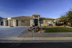View of front of home with driveway, stone siding, an attached garage, stucco siding, and a tile roof