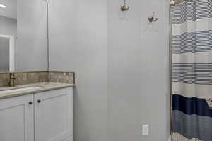 Full bathroom with vanity, a shower with shower curtain, and decorative backsplash