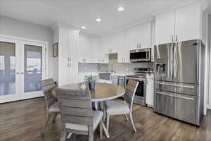 Dining room with dark wood-type flooring, french doors, and recessed lighting