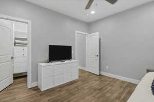 Unfurnished bedroom with a spacious closet, dark wood-type flooring, ceiling fan, and recessed lighting