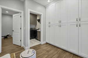 Washroom with light wood finished floors, cabinet space, recessed lighting, and separate washer and dryer
