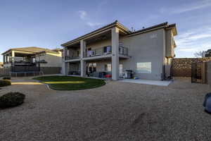 Back of house with a trampoline, stucco siding, a balcony, a patio, and a tile roof