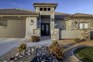 Mediterranean / spanish-style home featuring stone siding, stucco siding, an attached garage, concrete driveway, and a tile roof