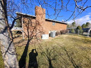 View of home's exterior featuring a chimney, brick siding, a fenced backyard, and a gate