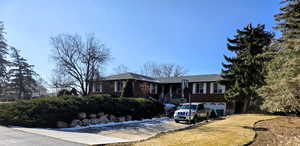 Ranch-style house featuring driveway, brick siding, an attached garage, and a front lawn
