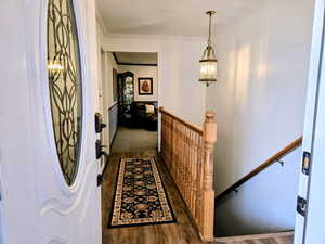 Corridor with dark wood-style floors, an upstairs landing, and ornamental molding