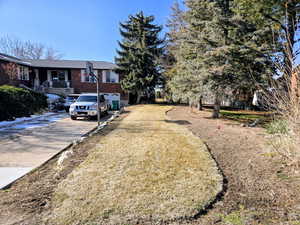 View of grassy yard with driveway, covered porch, and a garage