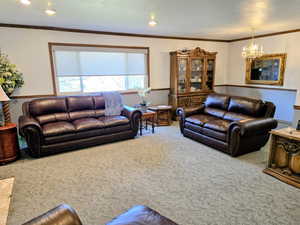 Living room featuring crown molding, carpet, a chandelier, and recessed lighting