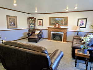 Carpeted living room with crown molding, a high end fireplace, and recessed lighting