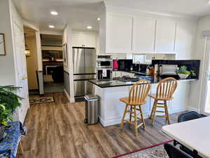 Kitchen with stainless steel appliances, recessed lighting, dark stone countertops, white cabinets, and dark wood finished floors