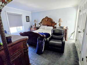 Bedroom with crown molding and dark carpet