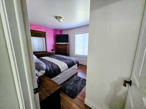 Bedroom with dark wood-style floors and baseboards