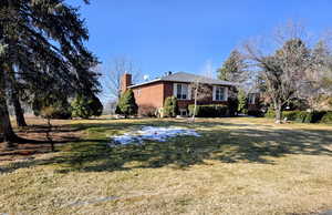 View of front of house featuring a chimney, a front lawn, and brick siding