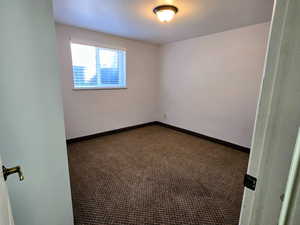 Carpeted spare room featuring baseboards