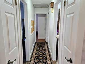 Hall featuring attic access and dark wood-type flooring