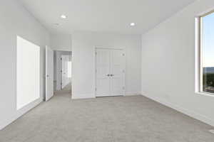 Unfurnished bedroom featuring light carpet, recessed lighting, and a closet
