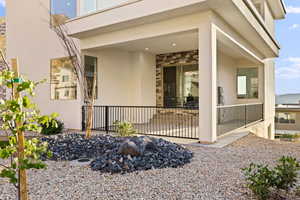 Entrance to property with stucco siding, stone siding, and a patio area