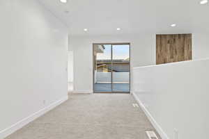 Empty room with light carpet and recessed lighting