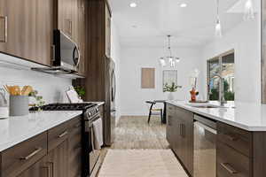 Kitchen with appliances with stainless steel finishes, hanging light fixtures, modern cabinets, light wood-style flooring, and recessed lighting