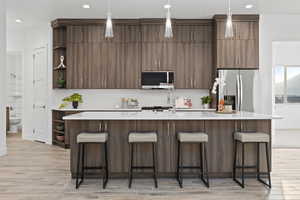 Kitchen with open shelves, appliances with stainless steel finishes, wood finish floors, light stone counters, and recessed lighting