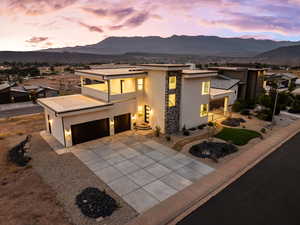Modern home featuring stucco siding, stone siding, a mountain view, and concrete driveway