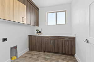 Laundry area featuring wood tiled floors, cabinet space, and electric dryer hookup