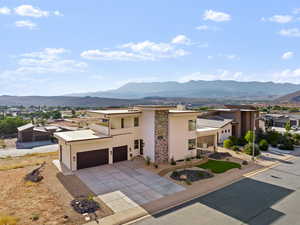 View of front of home with stucco siding, a mountain view, driveway, and stone siding