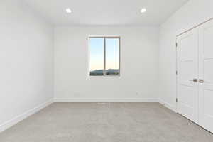 Unfurnished bedroom featuring light carpet, recessed lighting, and a closet
