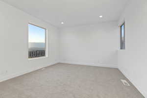 Empty room featuring light carpet, recessed lighting, and plenty of natural light