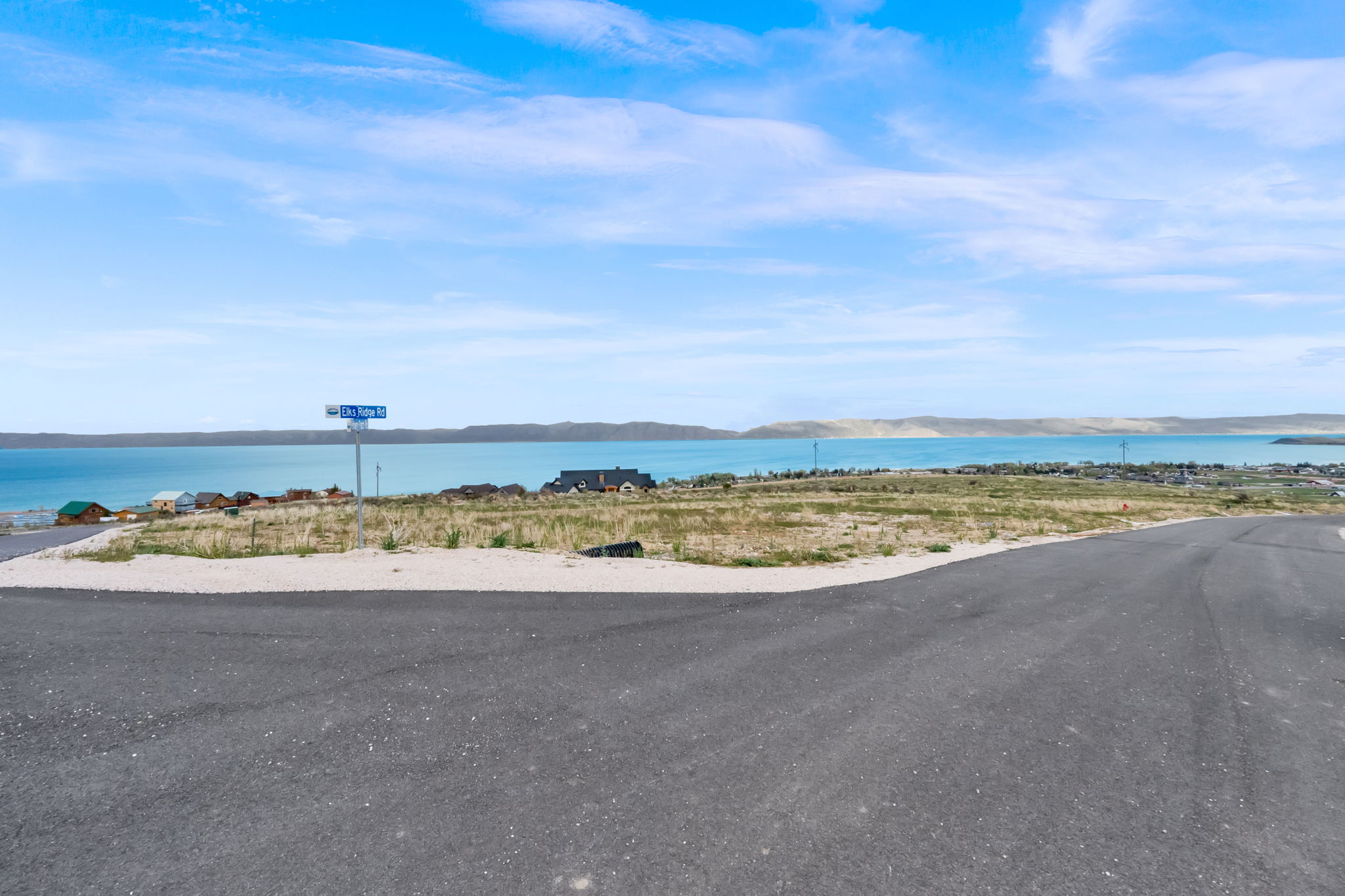Paved road with a gravel shoulder leading to a level lot