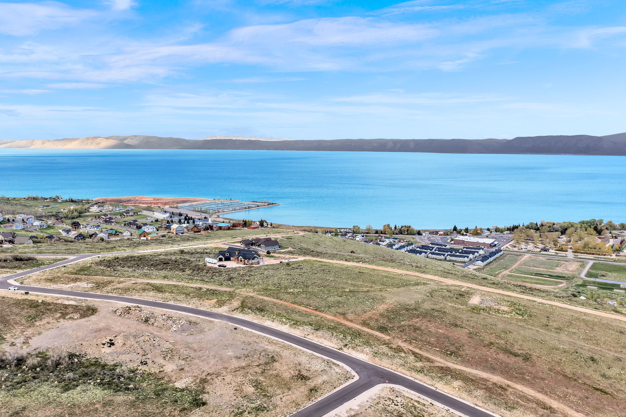 Expansive land parcel featuring paved roads, a gentle slope, and established homes