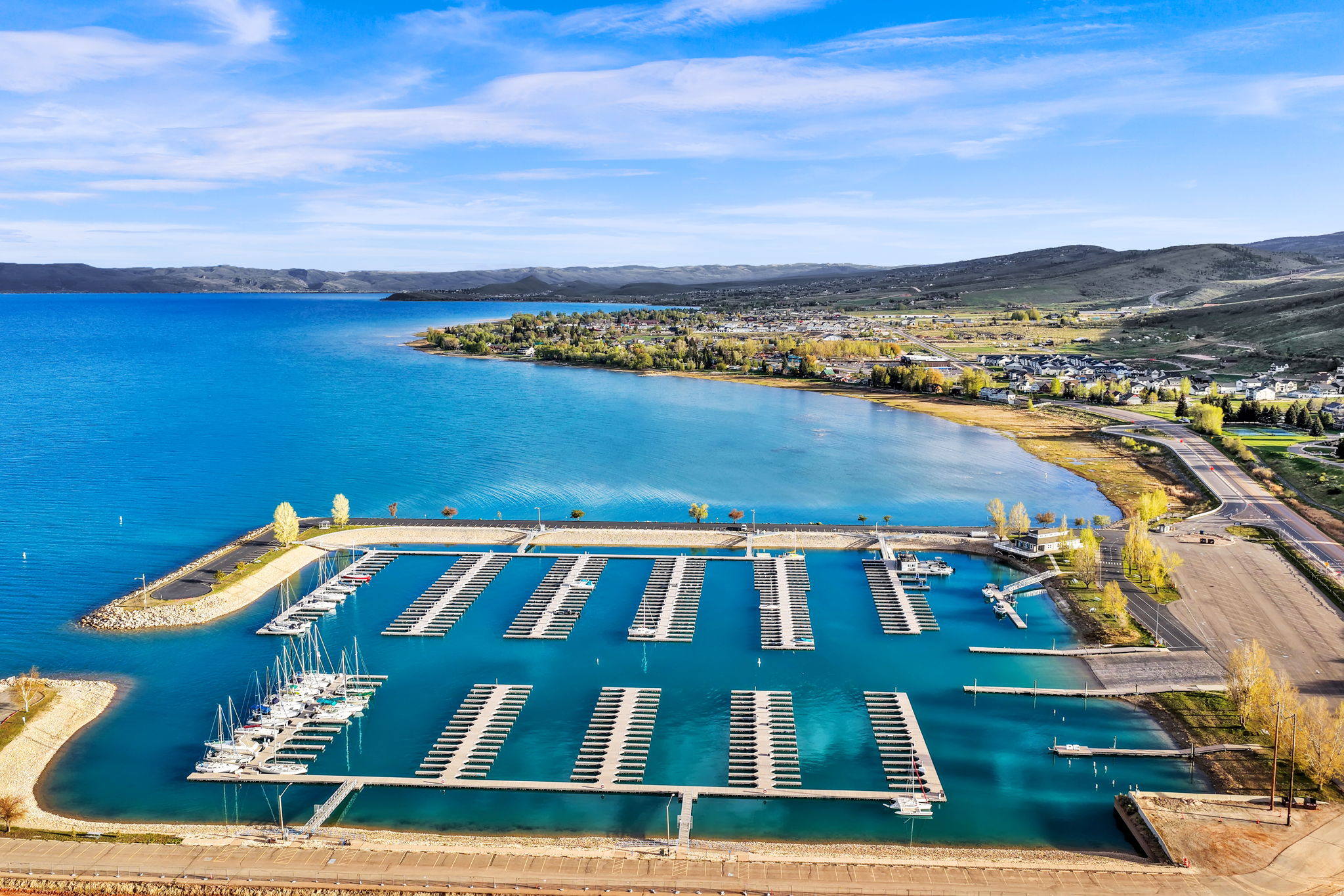 Aerial perspective showcasing a marina with numerous boat slips, set against a expansive body of water