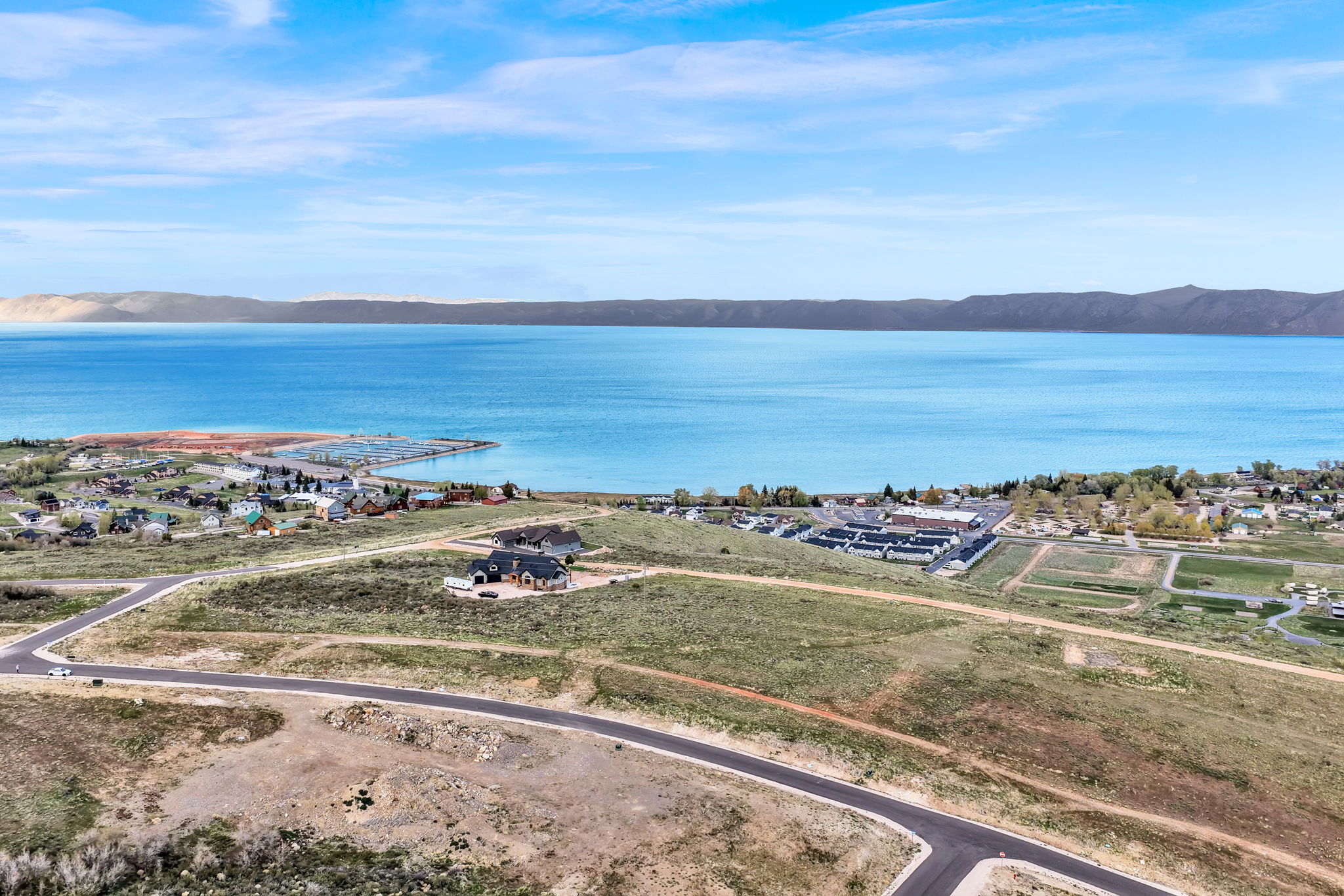 Expansive land parcel featuring paved road frontage, natural terrain, and distant water body
