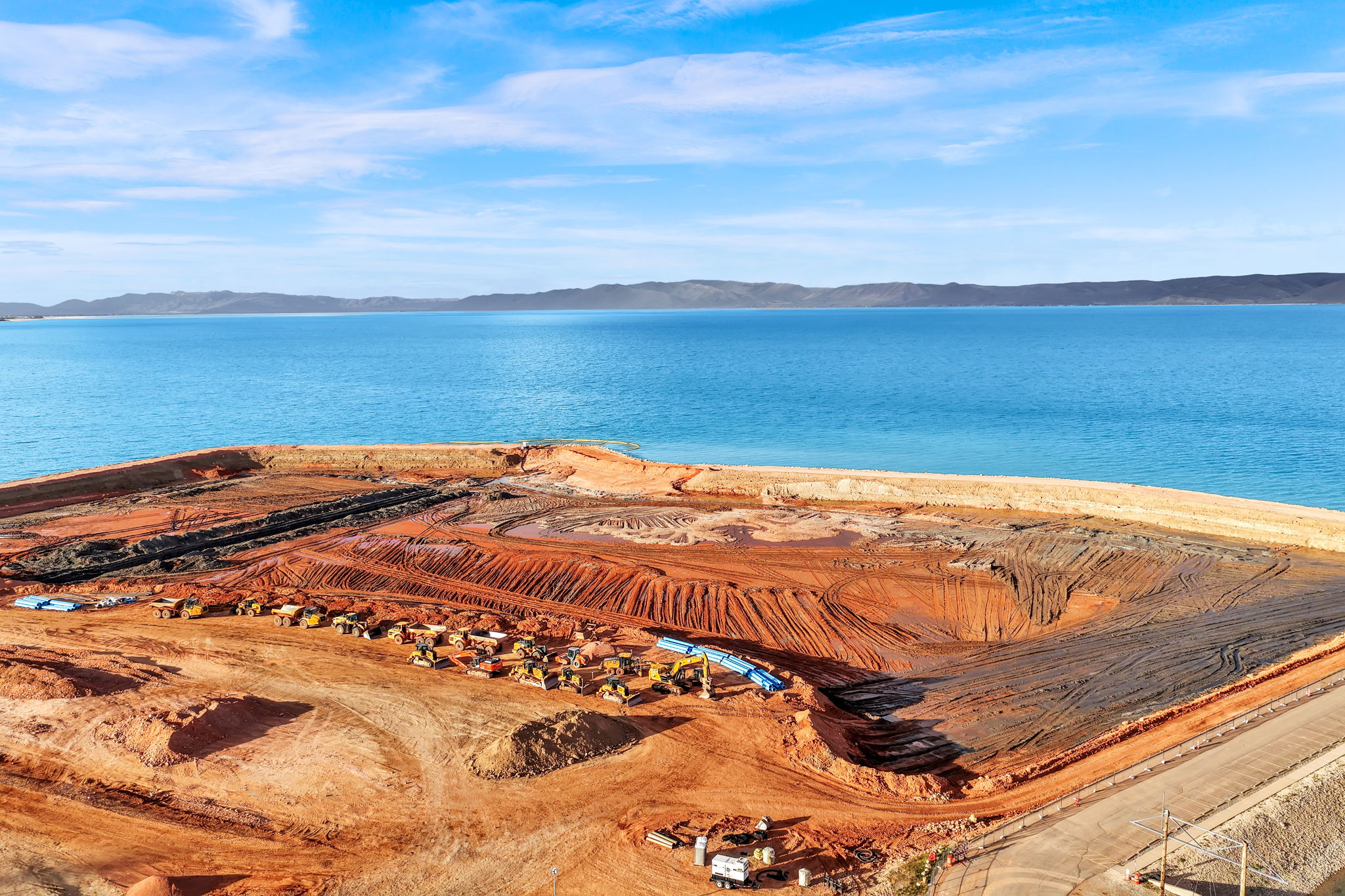 Expansive undeveloped land with direct water frontage, featuring a clear body of water and distant land formations