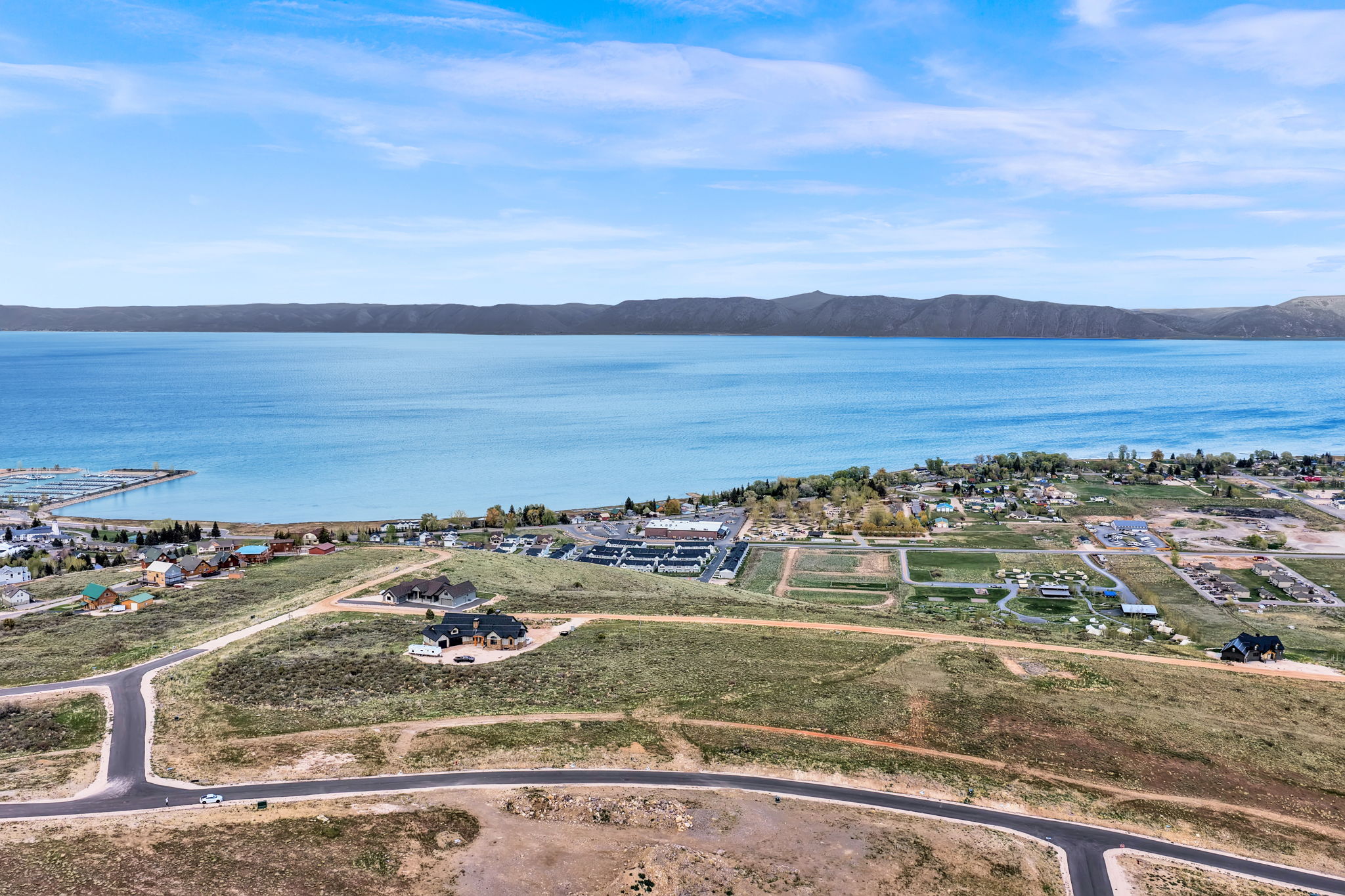 Expansive land parcel featuring existing paved roads and a serene lake backdrop